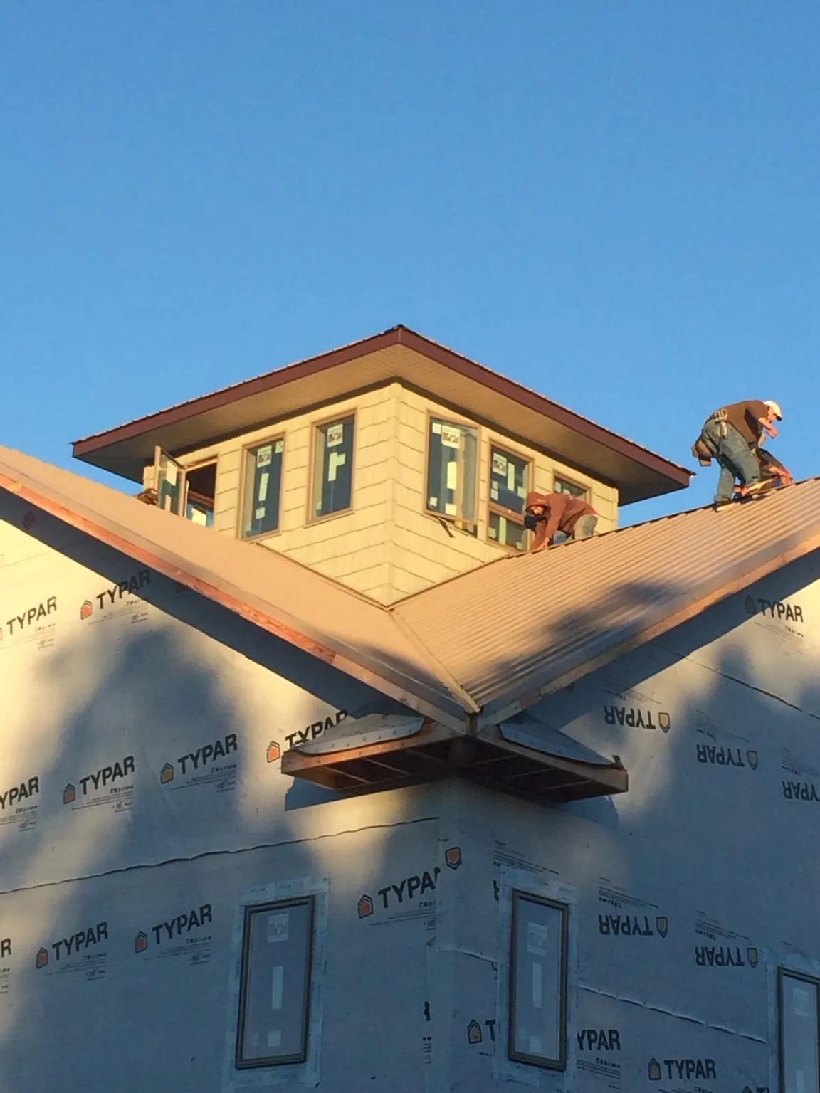 Roofers working around a rooftop cupola on a new metal roof at sunset — Roof Waterproofing in Milroy by Roofing Brothers